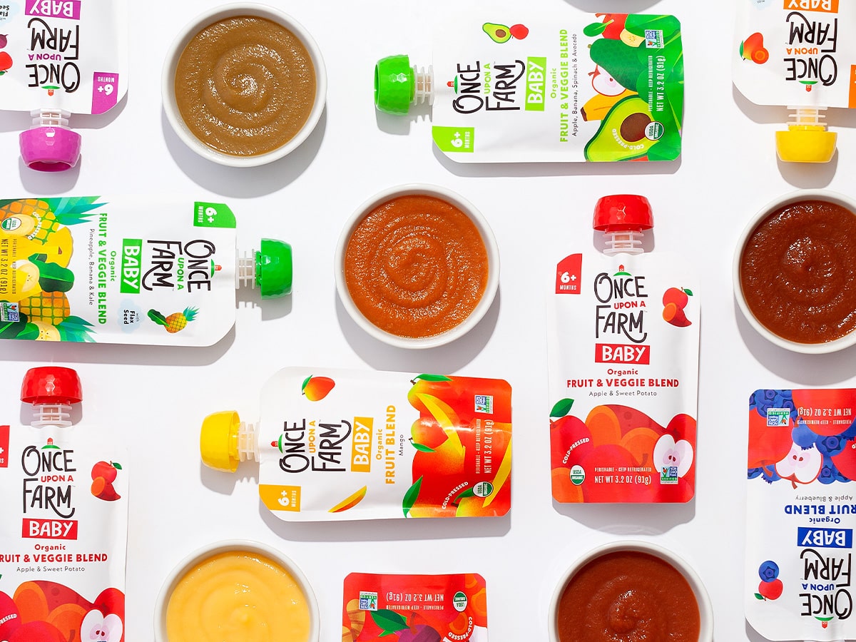 Once Upon a Farm baby food pouches, arranged next to the purees in bowls