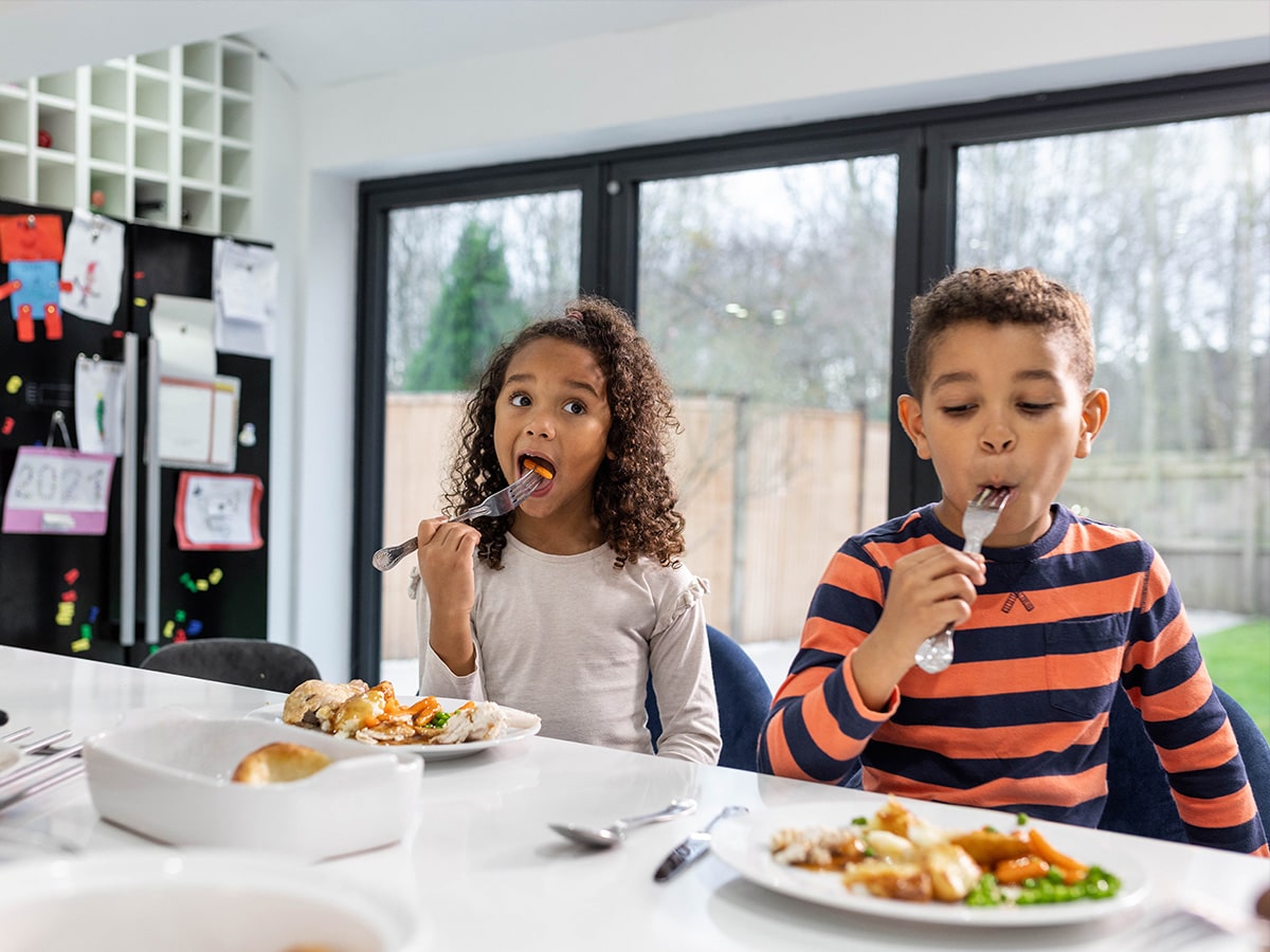 Two kids eating dinner at the kitchen counter
