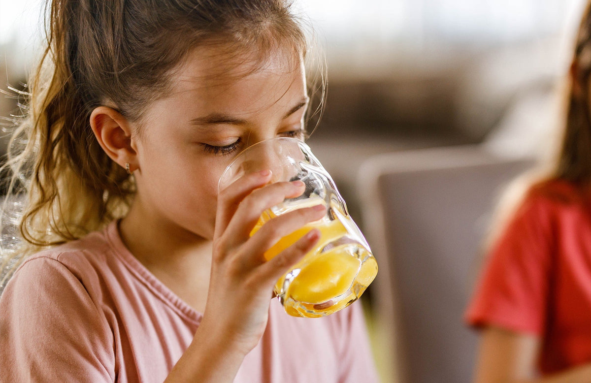 girl drinking a glass of orange juice