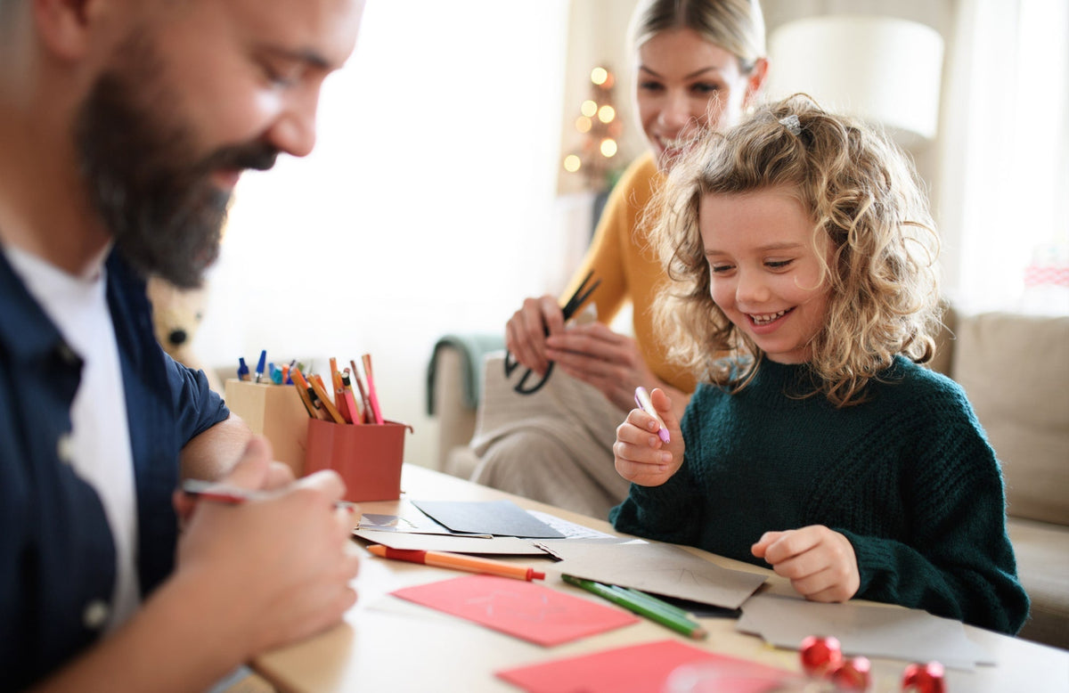 mom, dad, and daughter creating homemade cards