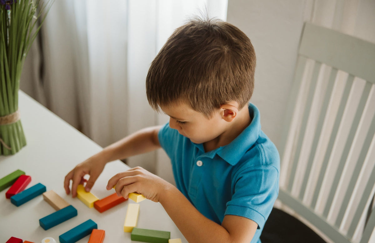 child playing with wooden blocks at a table