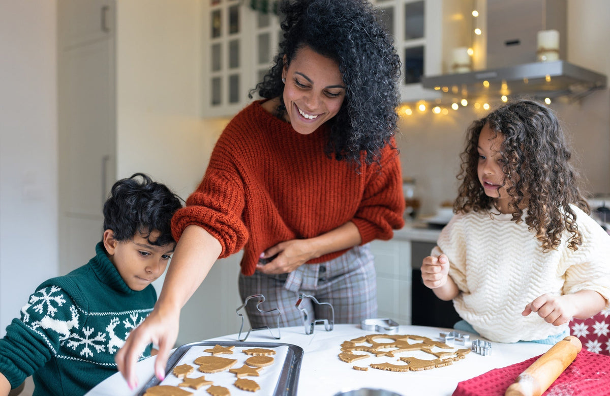 mom and two kids shaping holiday cookies together