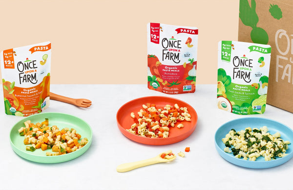 3 Once Upon a Farm Pasta Meals packages, behind 3 plates showing the cooked meals