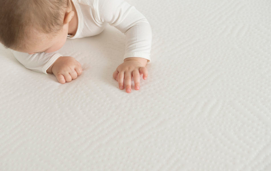 Newborn baby laying on a mattress. 