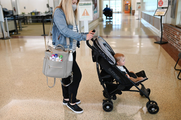 Mother and toddler at the airport with TSA approved snacks: Once Upon a Farm Fruit & Veggie blends. 