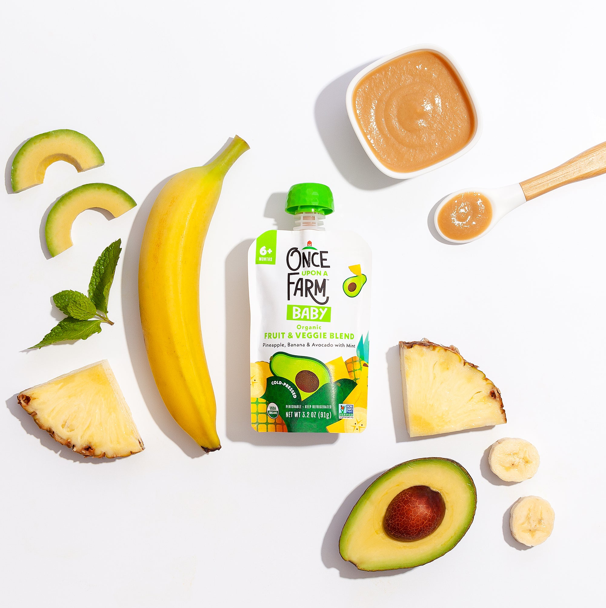 Front of Pineapple_Banana_Avocado_Mint packaging surrounded by real ingredients in the blend.