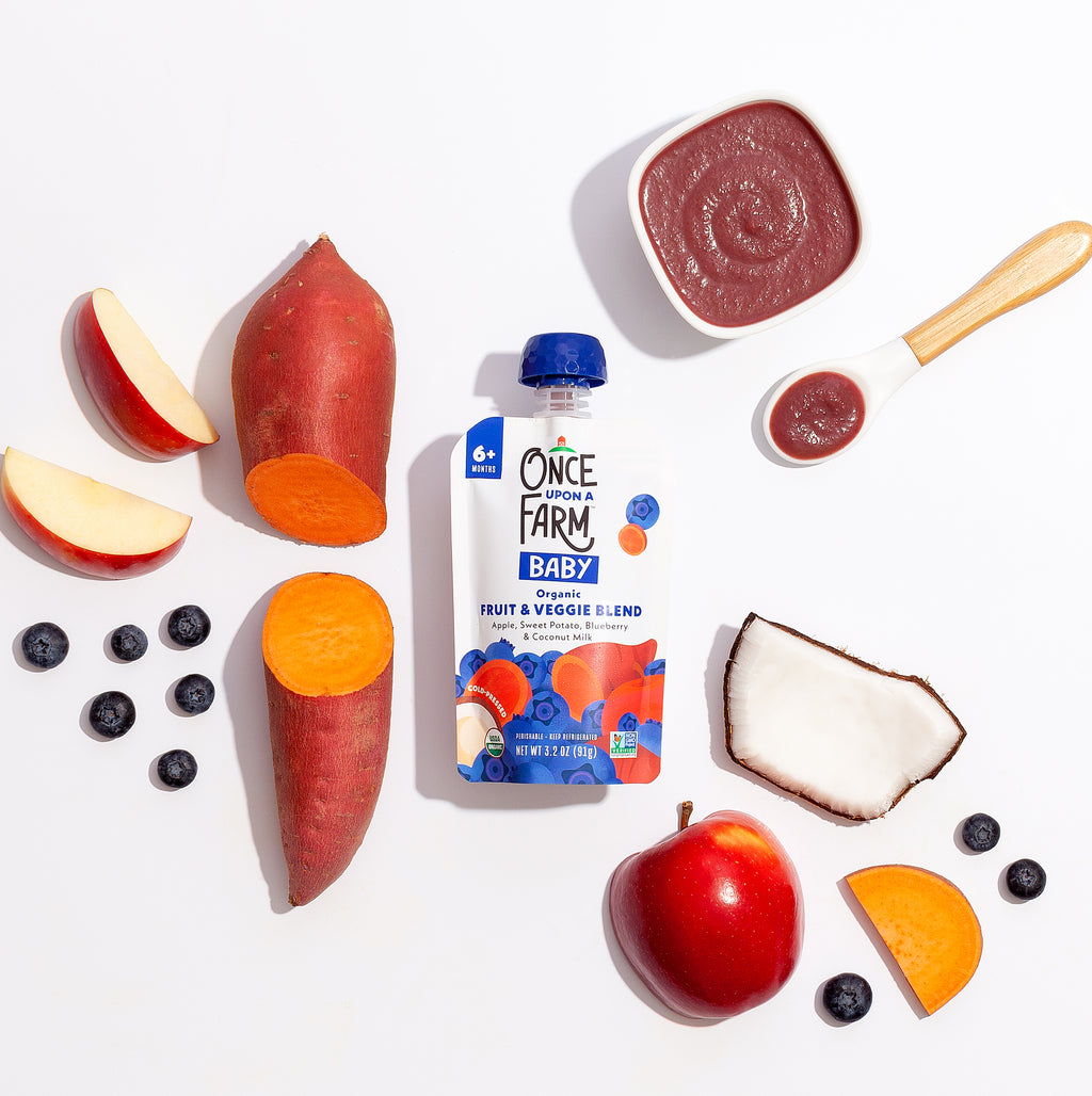 Front of Apple_Sweet_Potato_Blueberry_Coconut_Milk packaging surrounded by real ingredients in the blend.